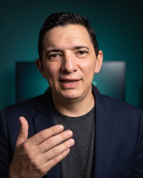Humberto Inciarte explicando, sobre fondo teal